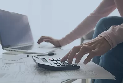 Woman typing on a computer with a calculator